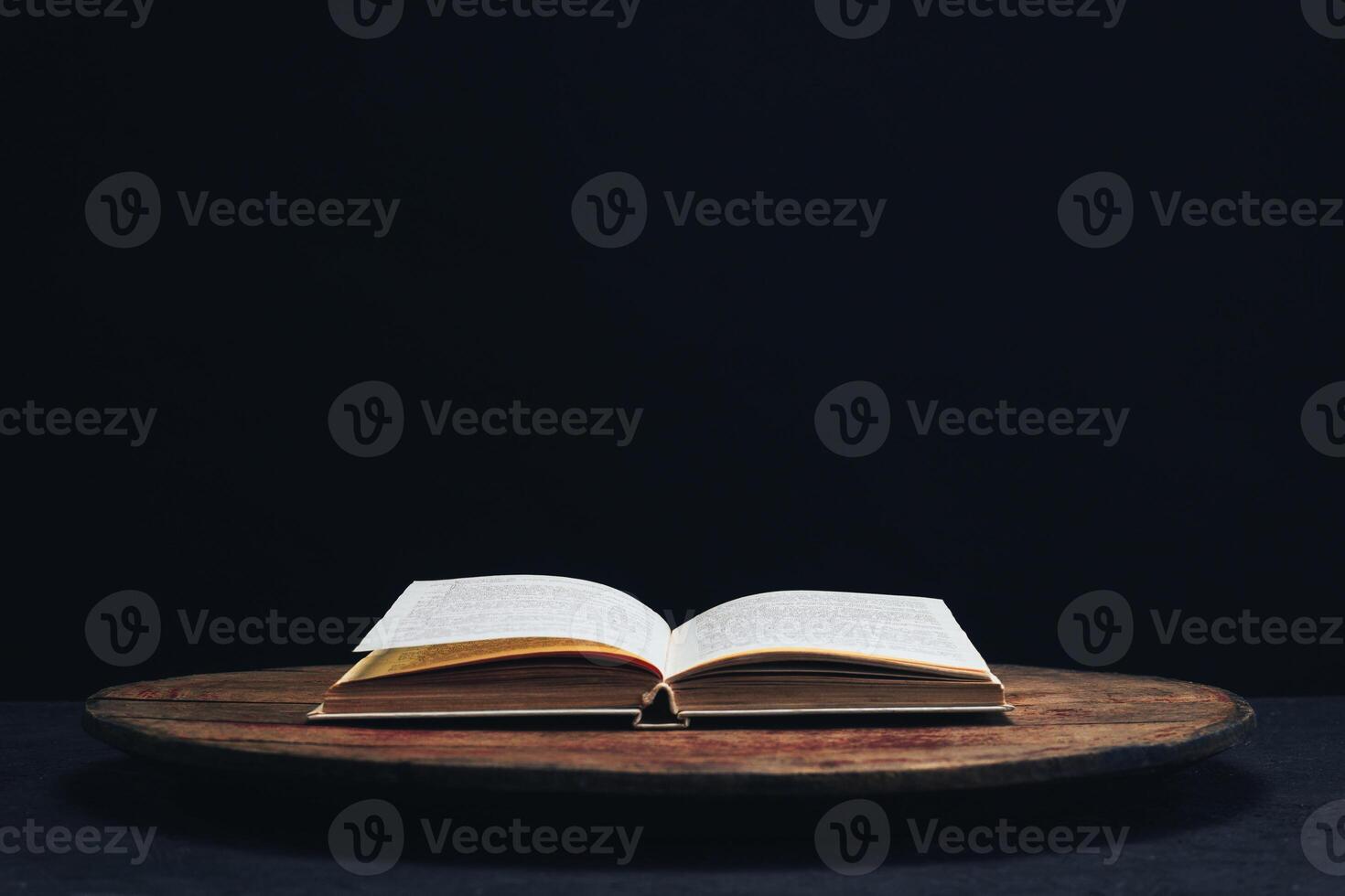 een Open oud boek Aan een ronde houten tafel. mooi donker achtergrond.. foto