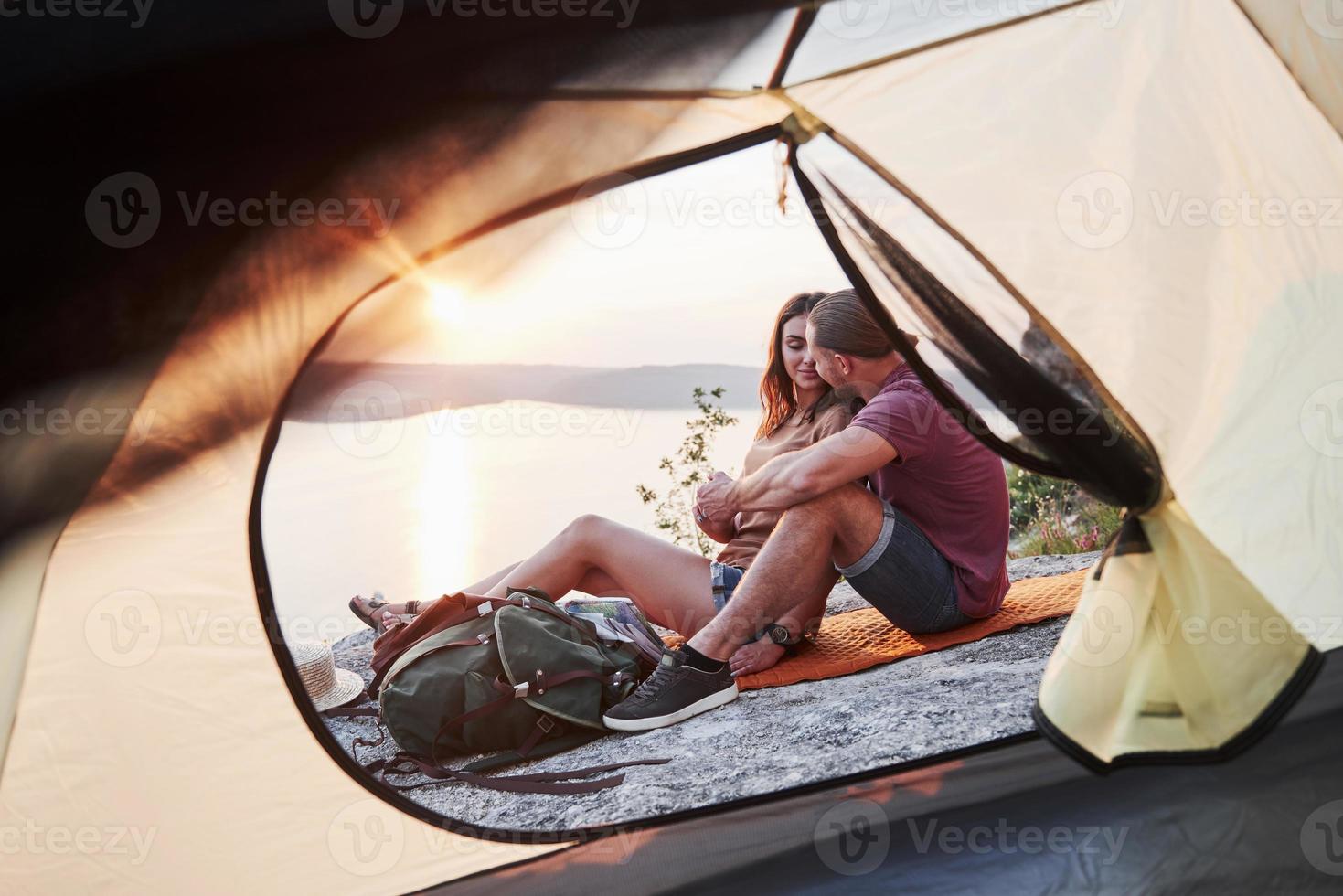uitzicht vanuit tent van paar liggend op het meer tijdens wandeltocht. avel lifestyle concept avontuurlijke vakanties buiten foto