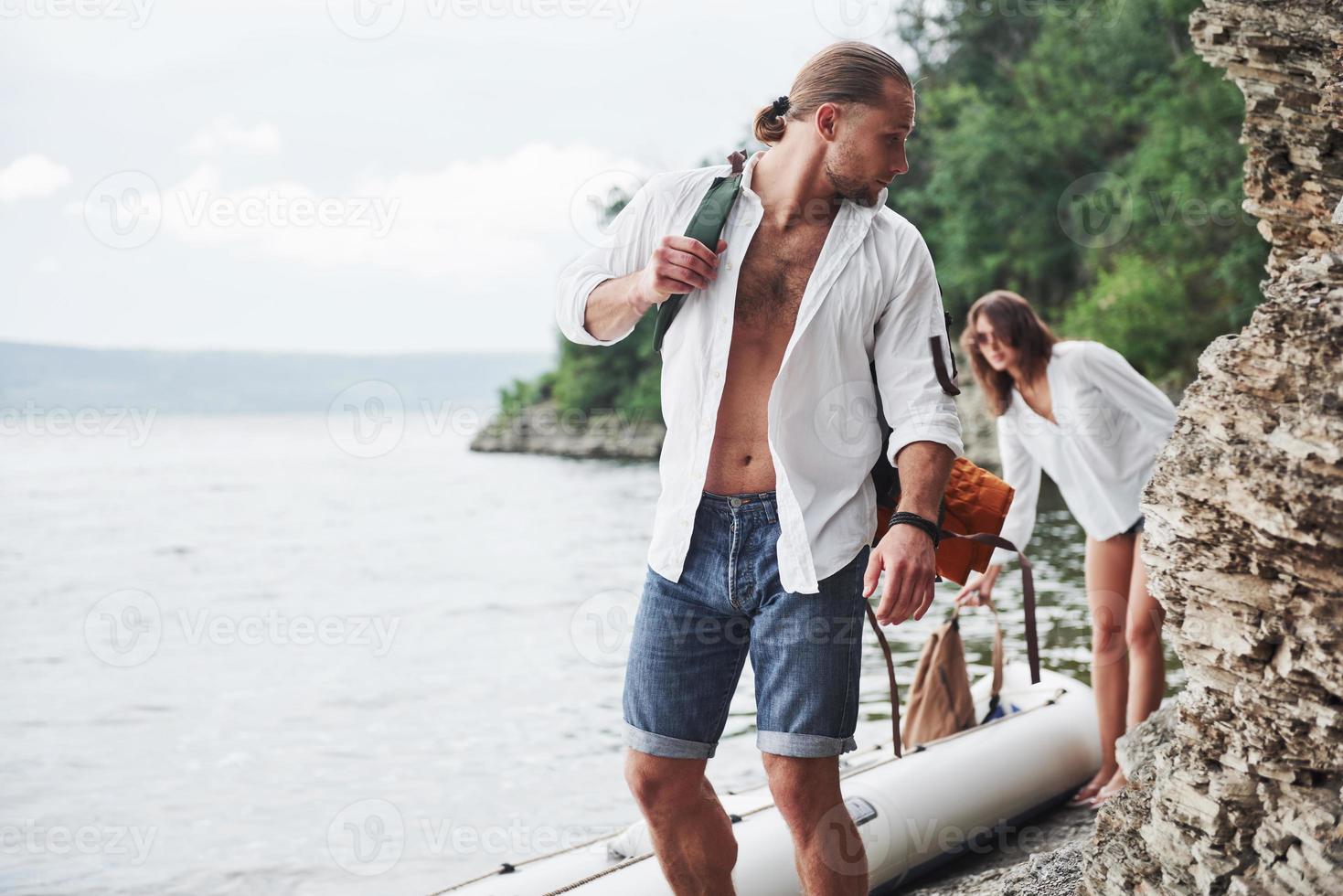 schattige jonge en paar op rivier achtergrond. een jongen en een meisje met rugzakken reizen per boot. reiziger zomer concept foto