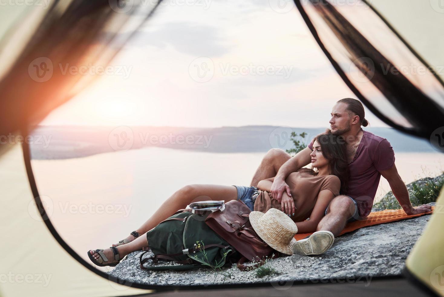 uitzicht vanuit tent van paar liggend op het meer tijdens wandeltocht. avel lifestyle concept avontuurlijke vakanties buiten foto