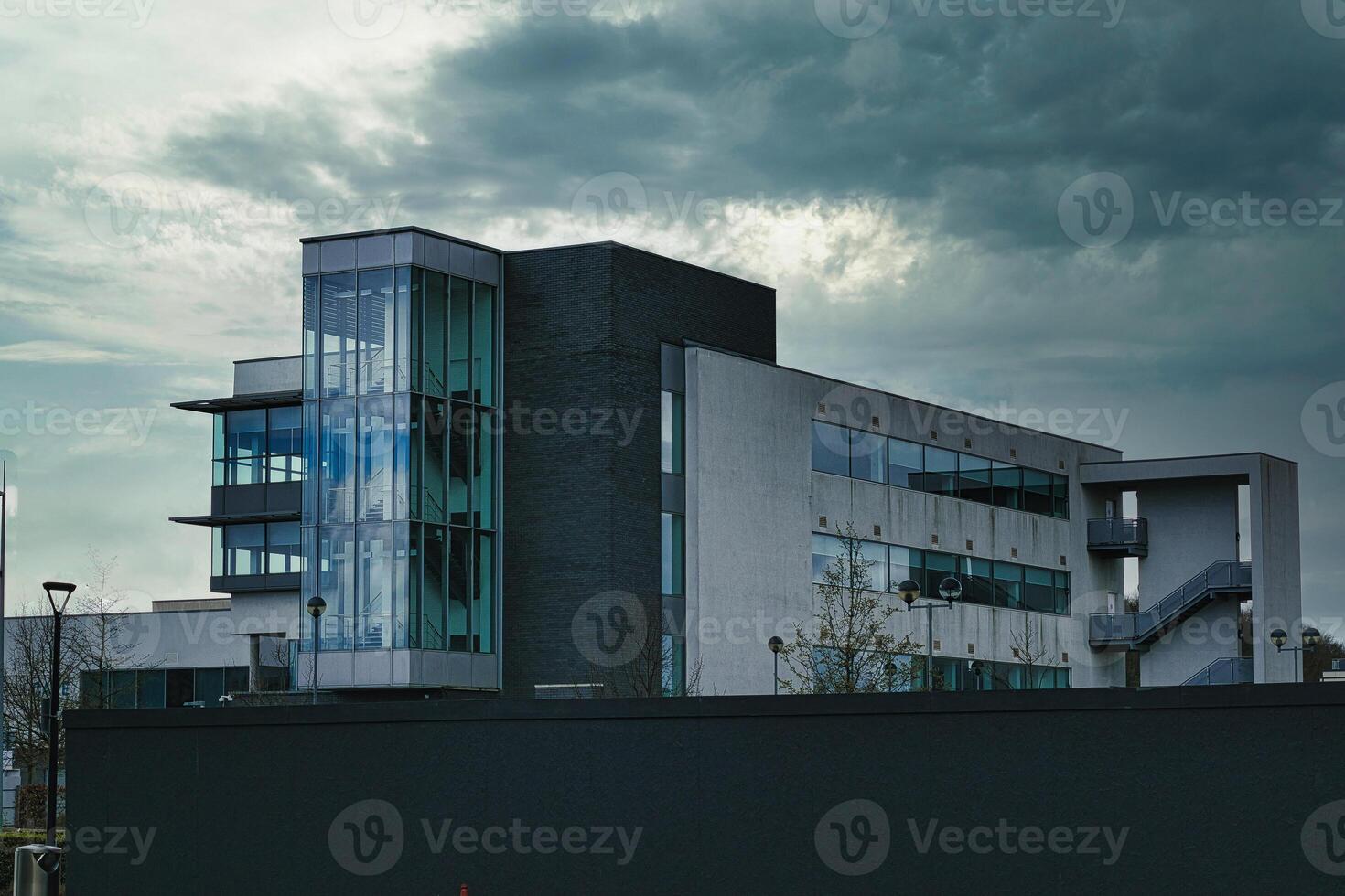 modern kantoor gebouw tegen een dramatisch bewolkt lucht, presentatie van hedendaags architectuur met een mengen van glas en beton elementen. foto