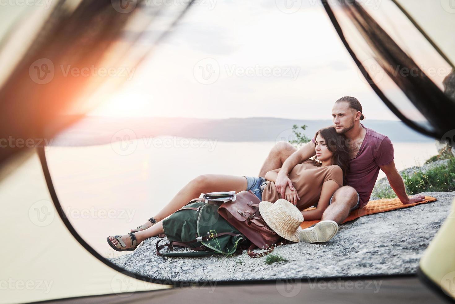 uitzicht vanuit tent van paar liggend op het meer tijdens wandeltocht. avel lifestyle concept avontuurlijke vakanties buiten foto