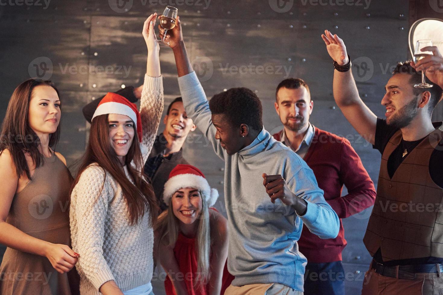 feest met vrienden. ze houden van kerst. groep vrolijke jonge mensen die sterretjes en champagnefluiten dragen die op nieuwjaarsfeest dansen en er gelukkig uitzien. concepten over saamhorigheid levensstijl foto