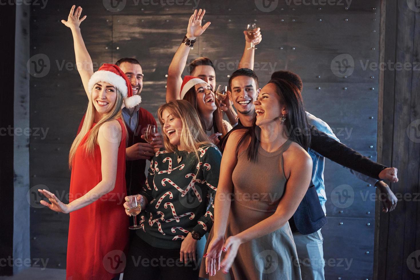 feest met vrienden. ze houden van kerst. groep vrolijke jonge mensen die sterretjes en champagnefluiten dragen die op nieuwjaarsfeest dansen en er gelukkig uitzien. concepten over saamhorigheid levensstijl foto