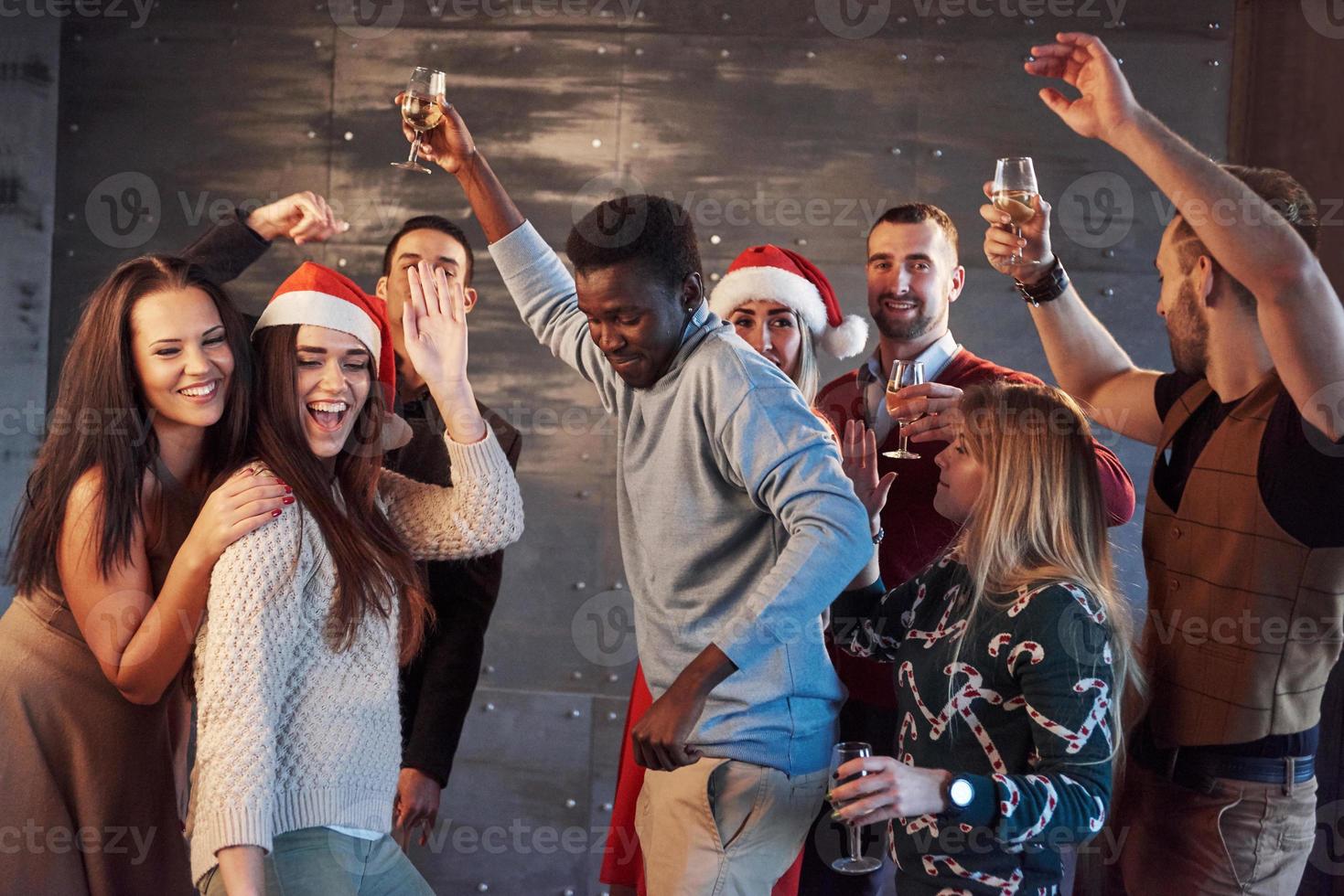 feest met vrienden. ze houden van kerst. groep vrolijke jonge mensen die sterretjes en champagnefluiten dragen die op nieuwjaarsfeest dansen en er gelukkig uitzien. concepten over saamhorigheid levensstijl foto