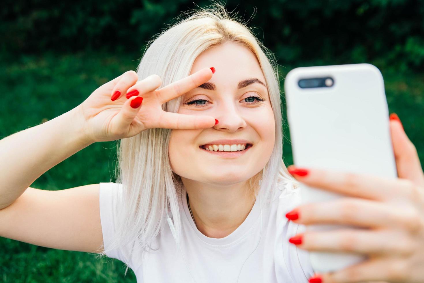 vrouw in hoofdtelefoons en smartphone in handen op groene achtergrond foto