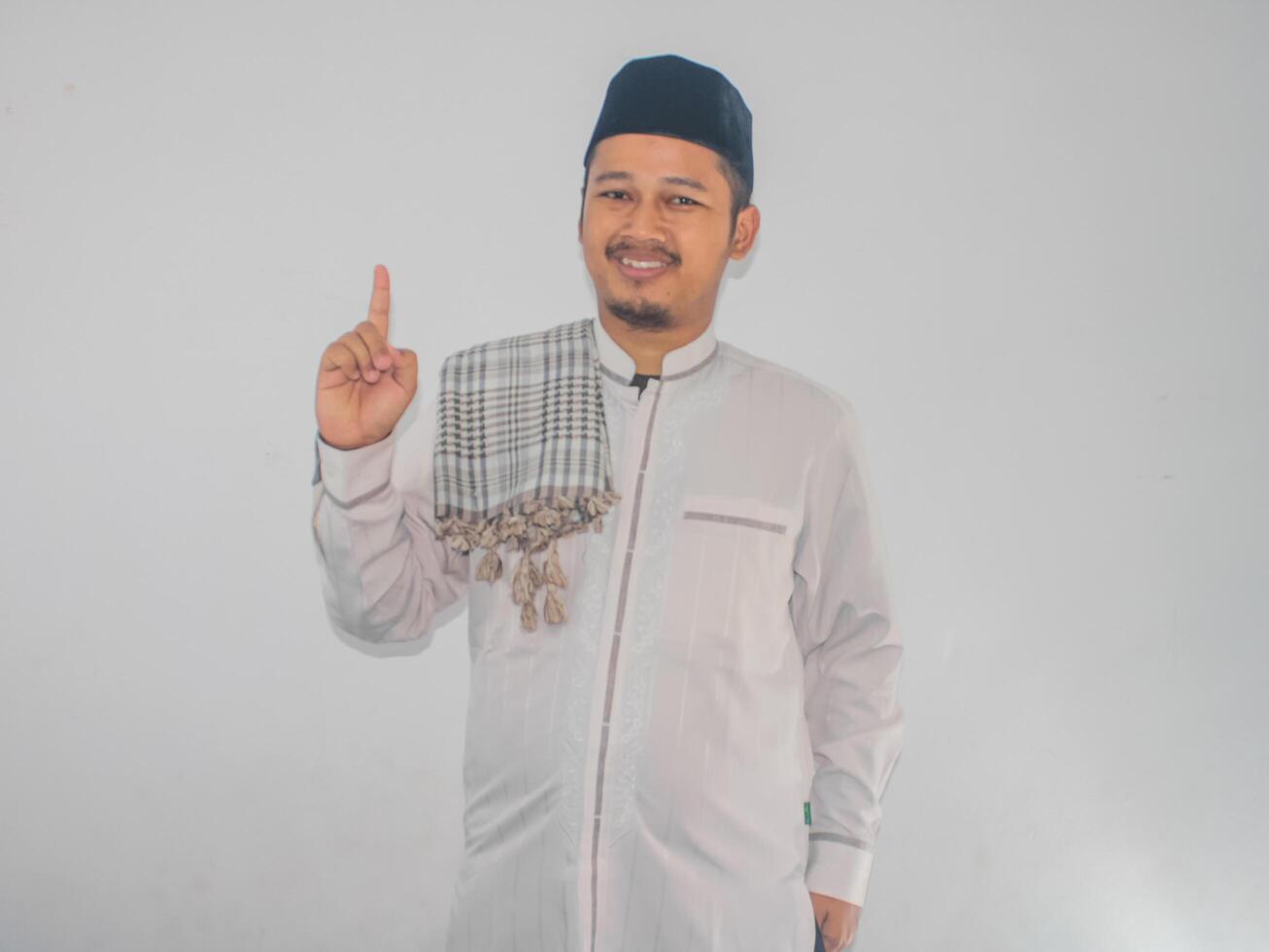 Moslim Aziatisch Mens glimlachen Bij de camera en tonen een vinger teken foto