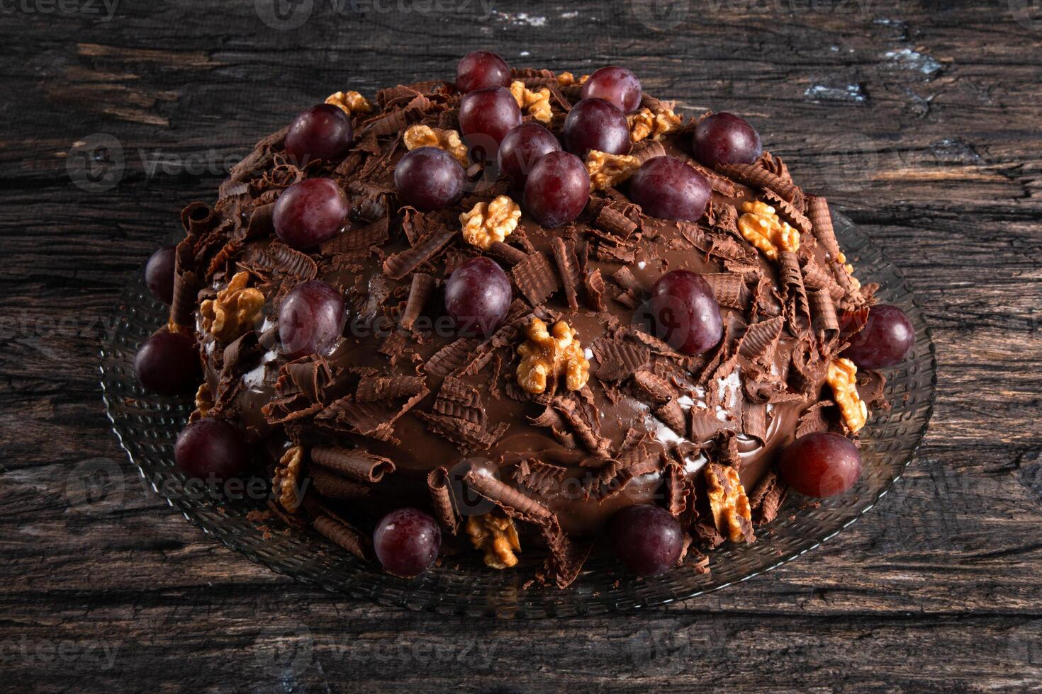 taart met chocola suikerglazuur en druiven Aan een rustiek achtergrond foto