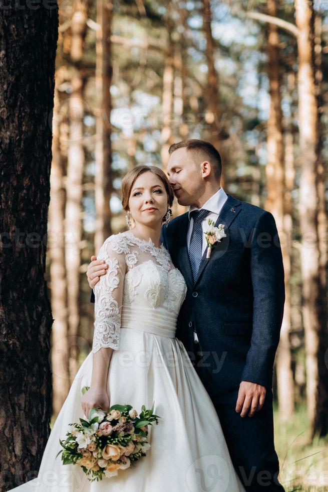 de bruid en bruidegom lopen in een dennenbos foto