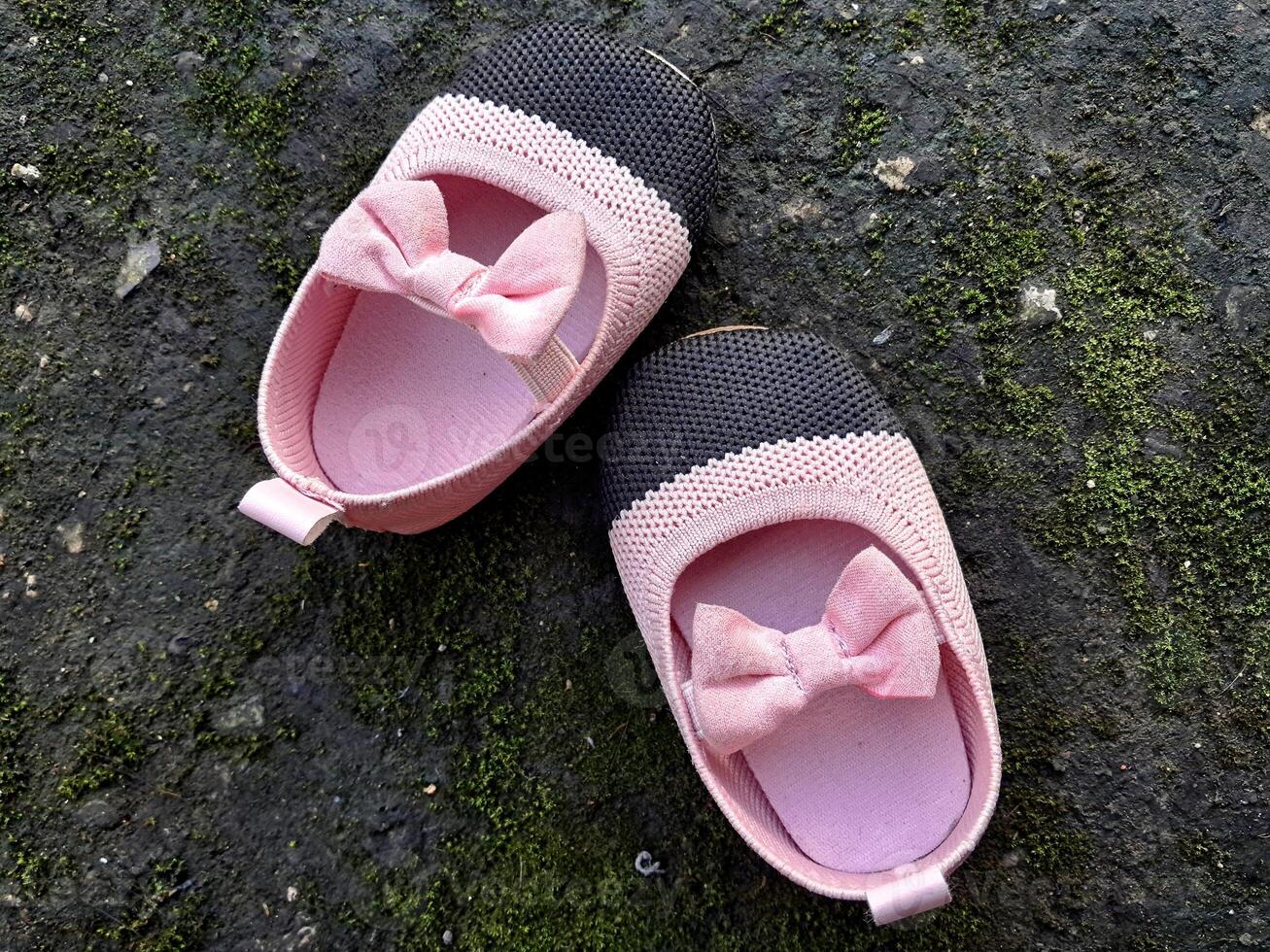 schattig weinig baby schoenen roze en zwart kleur Aan gips en mos planten achtergrond foto