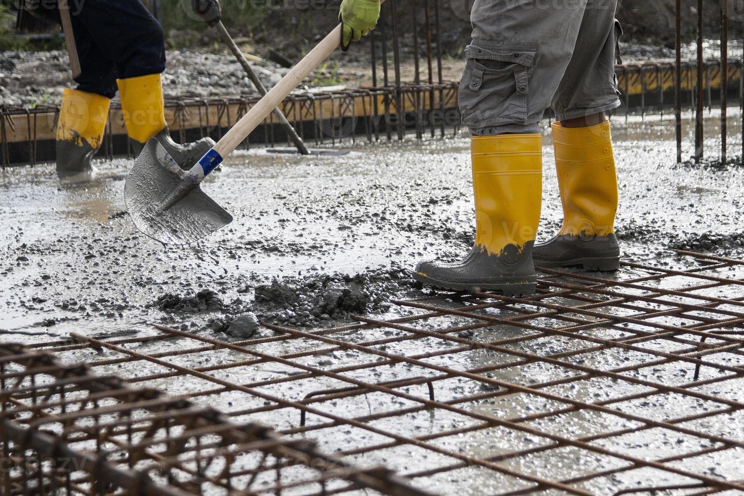 metselaars die het vers gestorte beton egaliseren om de fundamenten van een gebouw te leggen foto