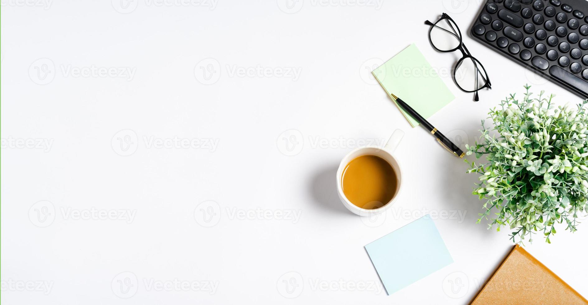 bovenaanzicht van koffie, boek, notitieboekje, pen, toetsenbord, telefoon op witte achtergrond foto
