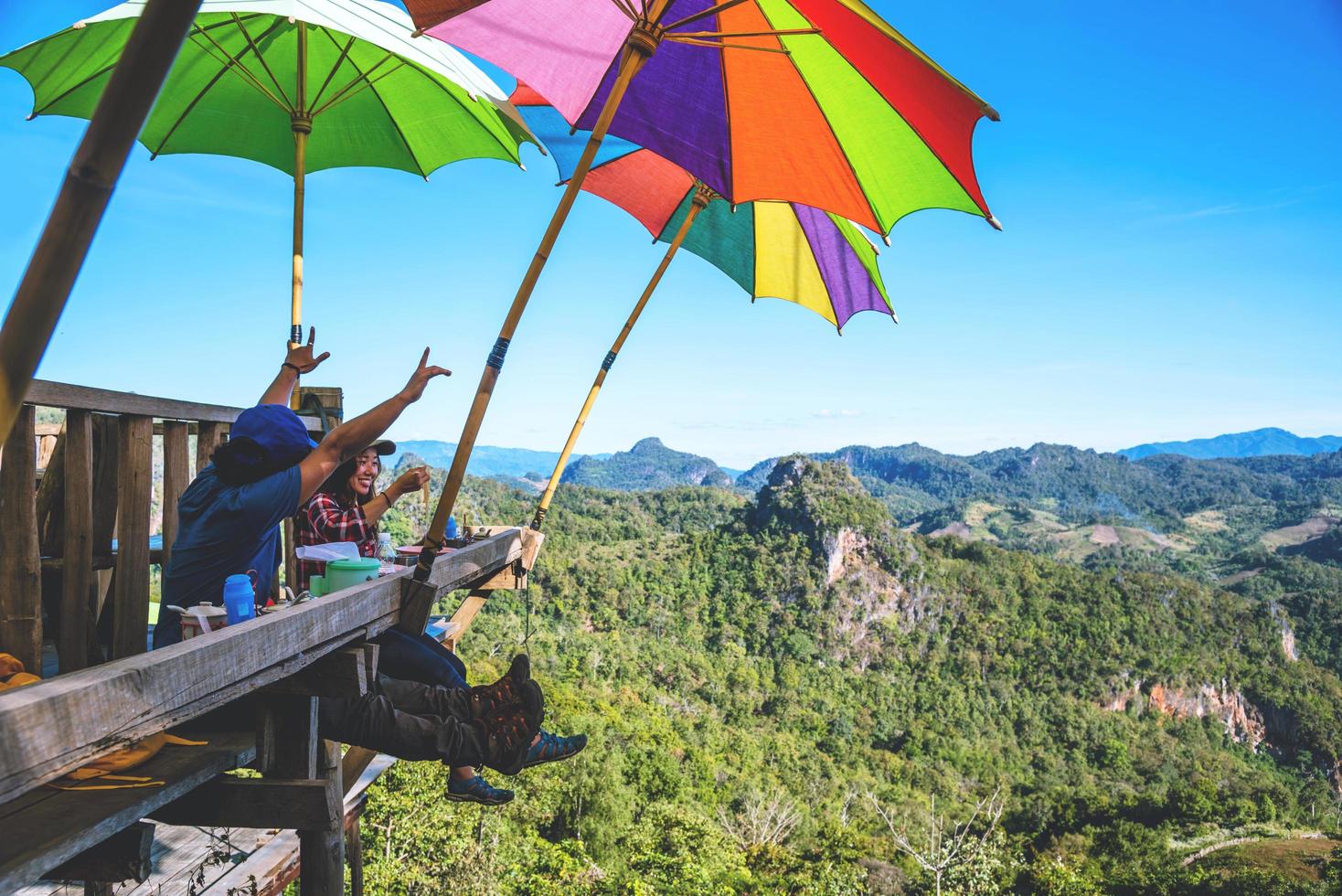 toeristen aziatisch paar zittend eten noedels op het houten platform en kijken schilderachtig uitzicht op prachtige natuur bergen bij verbod jabo, mae hong son, thialand. foto