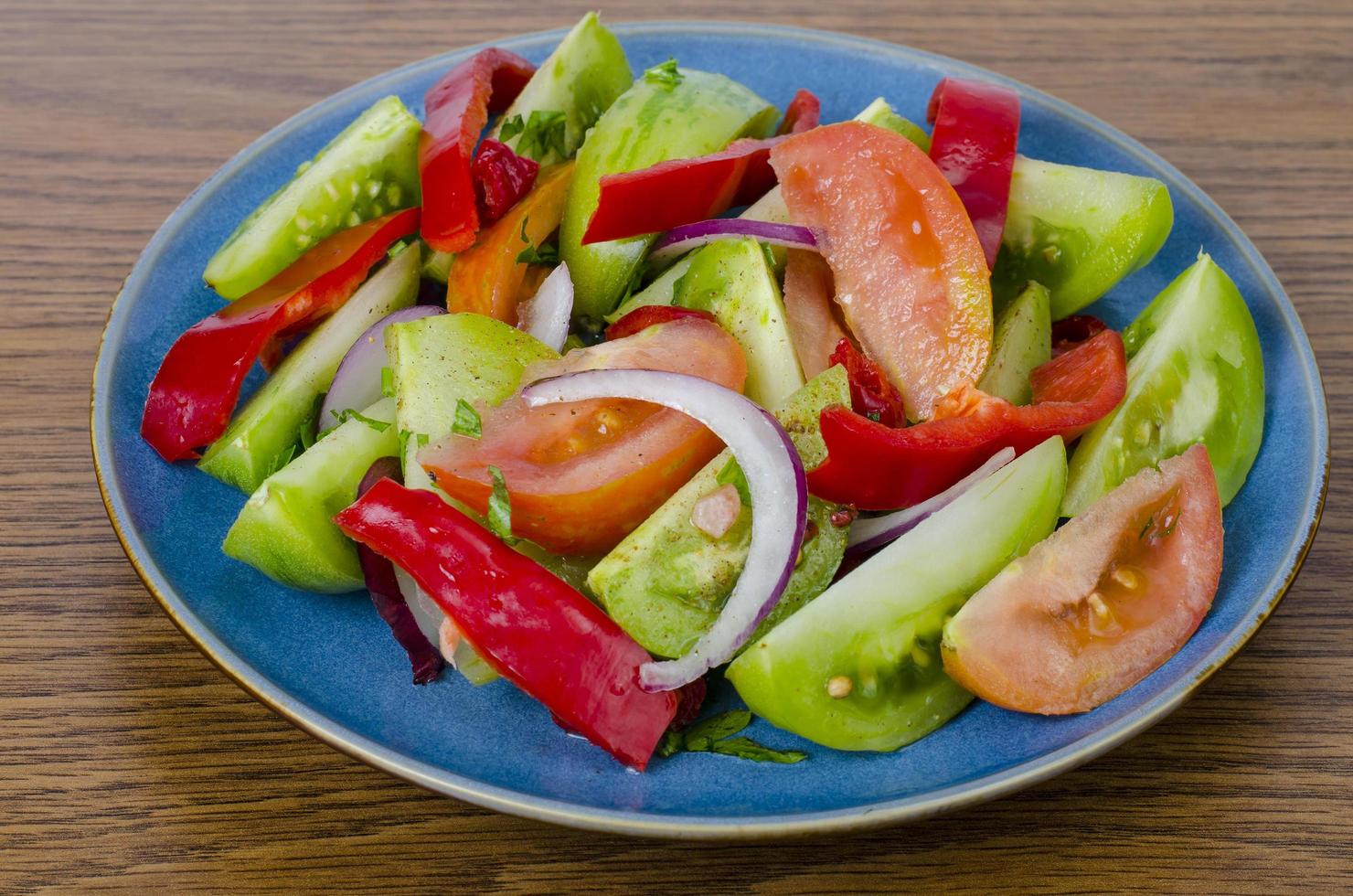 Vegetarische groentesalade op blauw bord, houten achtergrond foto