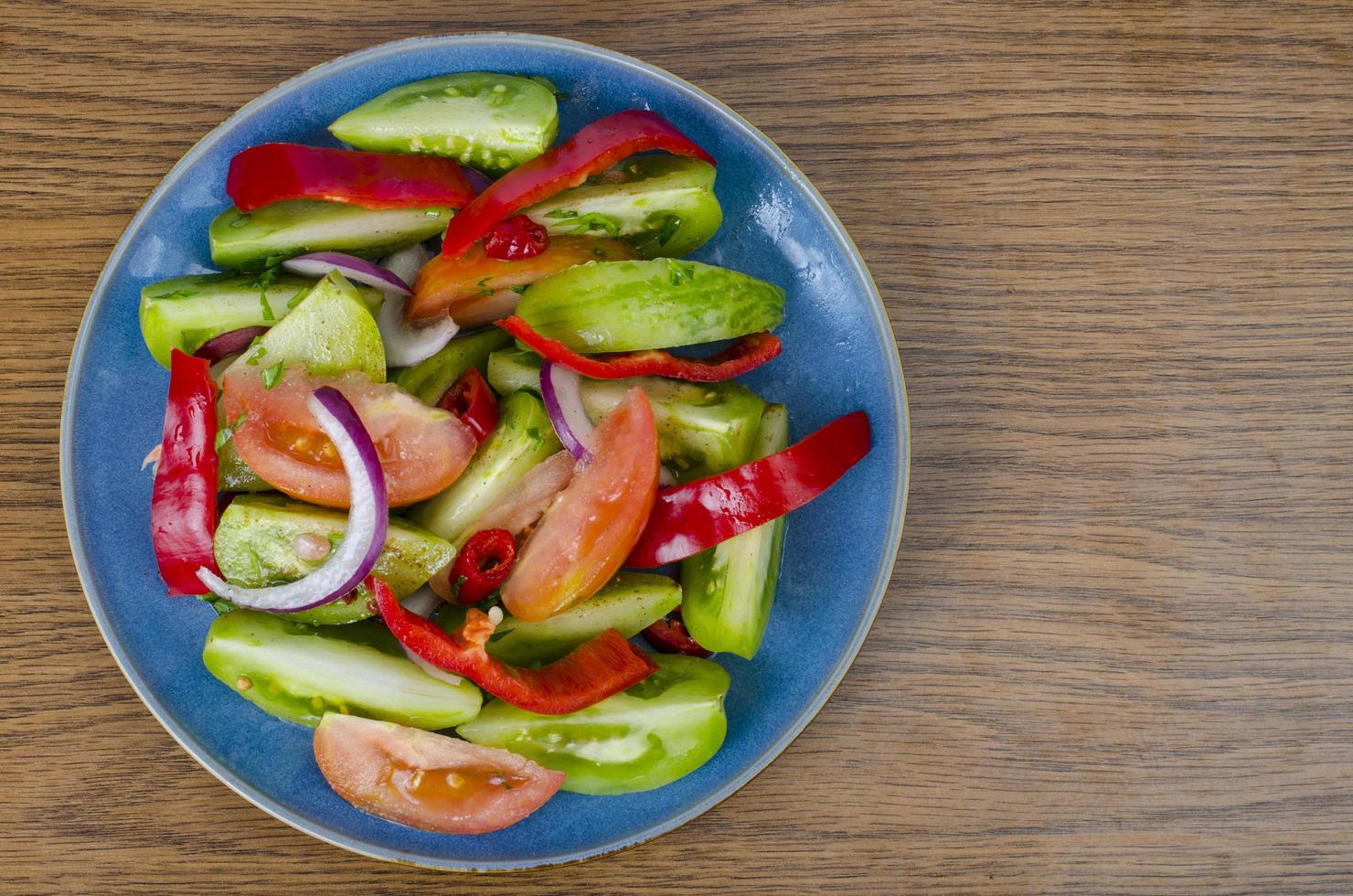 Vegetarische groentesalade op blauw bord, houten achtergrond foto