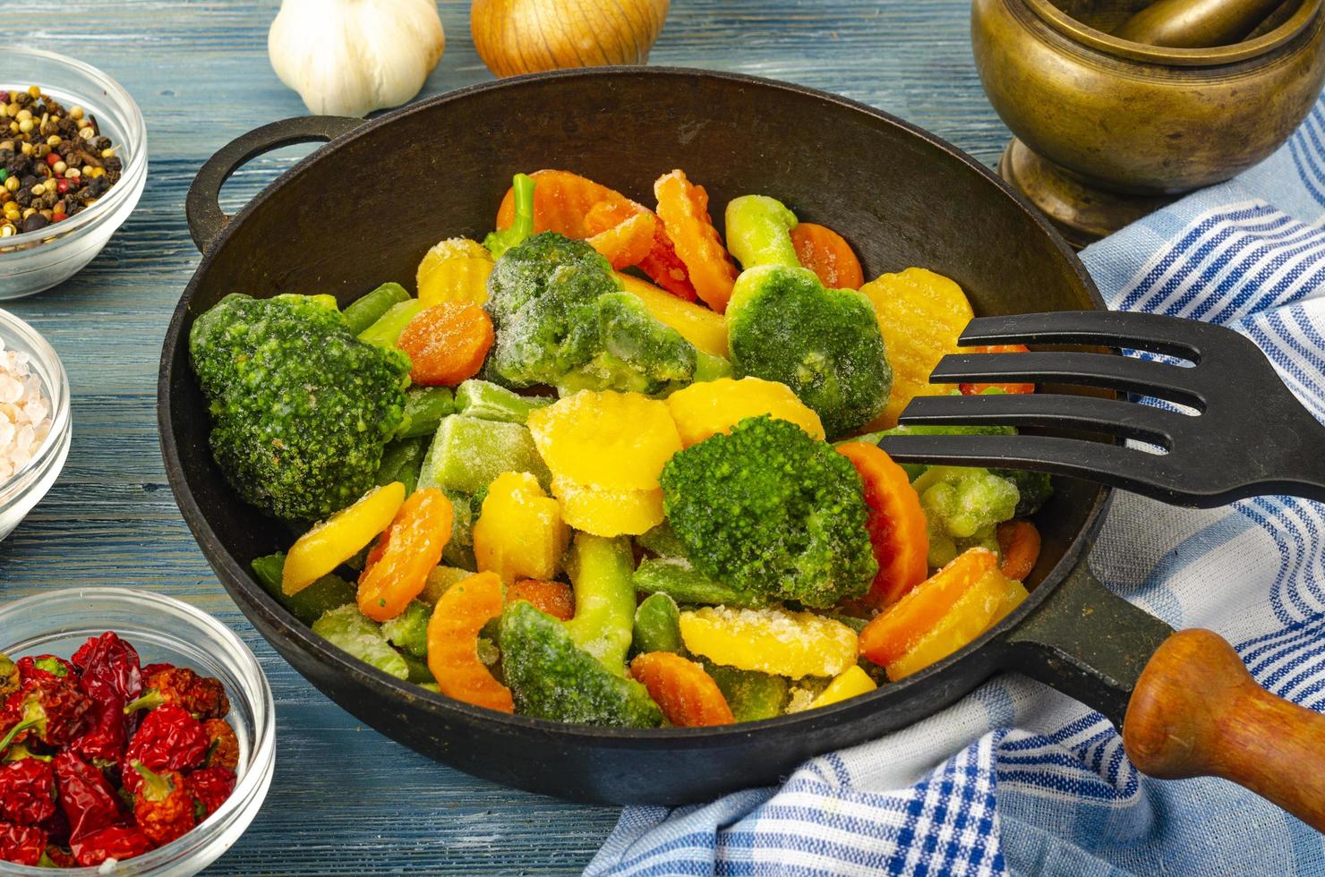 vegetarisch eten. mix van bevroren verse groenten om te frituren op blauwe houten achtergrond. studio foto