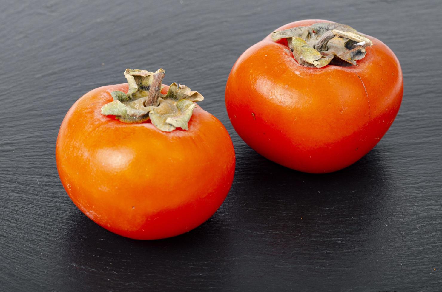 zoete sappige oranje persimmon op contrasterende zwarte achtergrond. studio foto