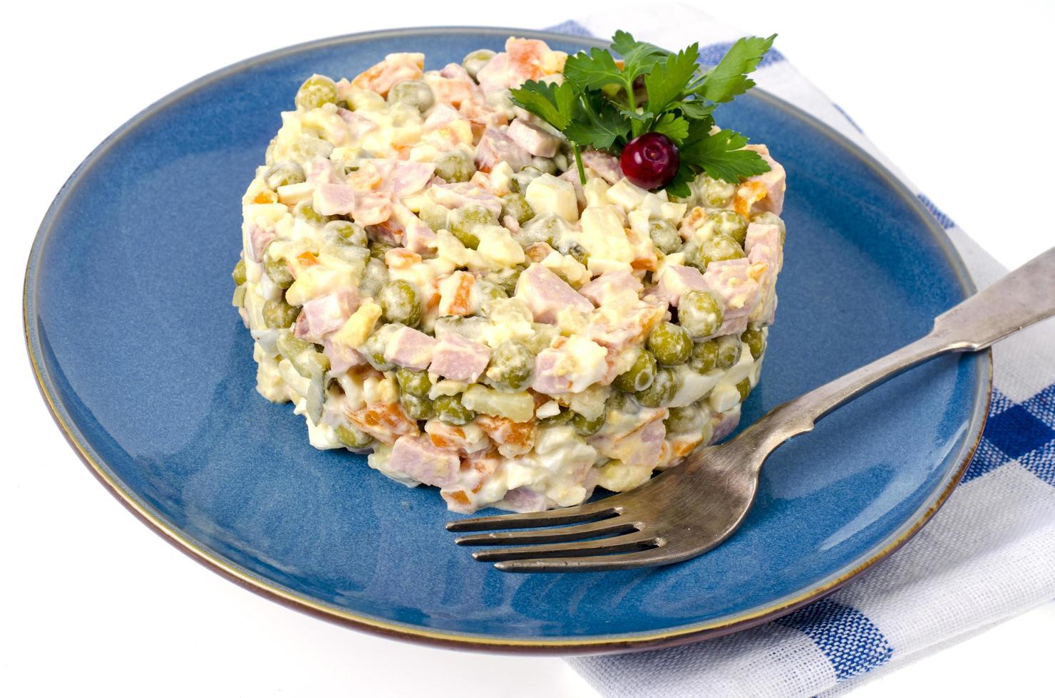 Russische groentesalade met erwten en mayonaise op blauw bord foto