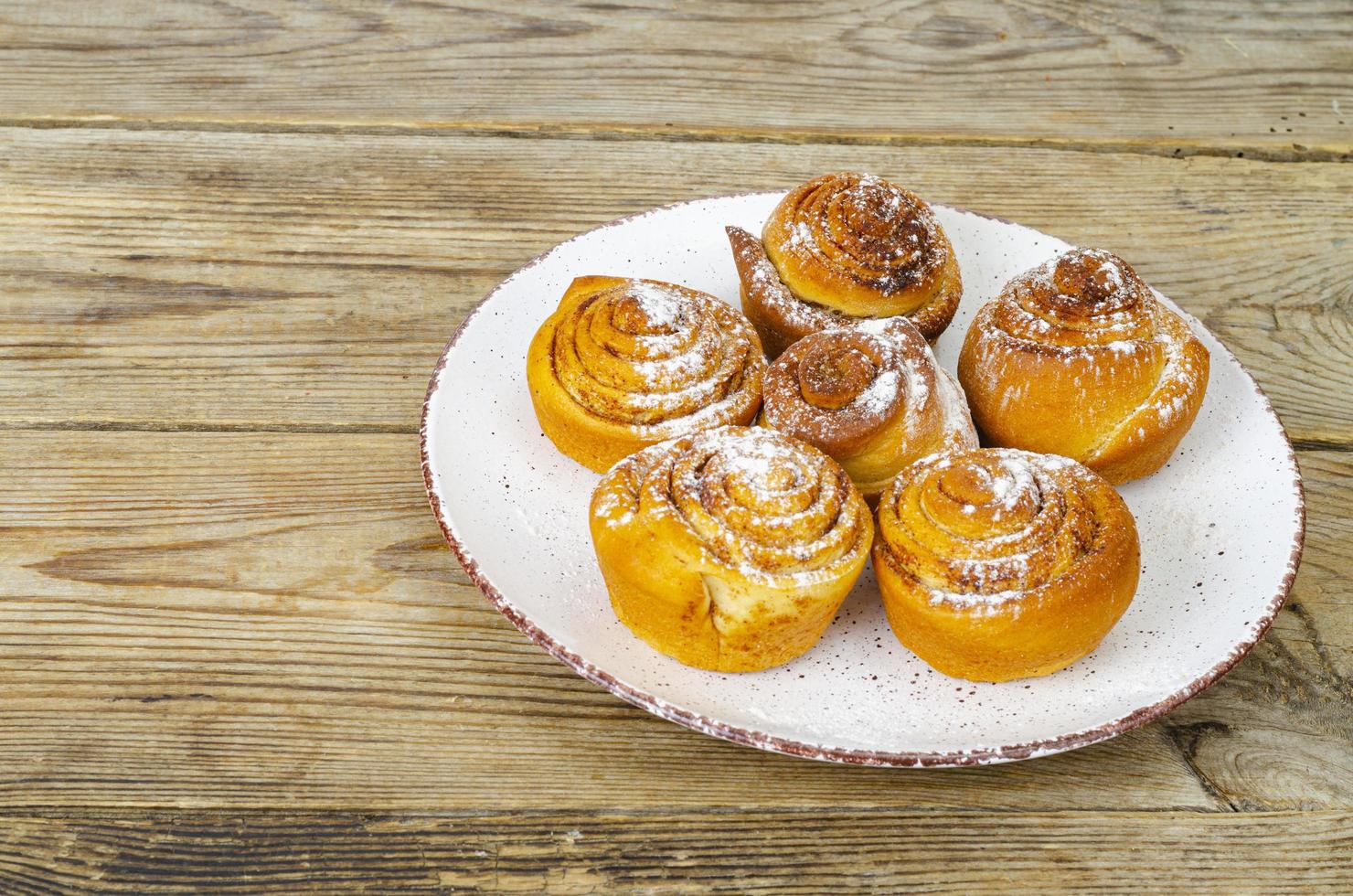 plaat van zelfgemaakte kaneelbroodjes op houten tafel. studio foto