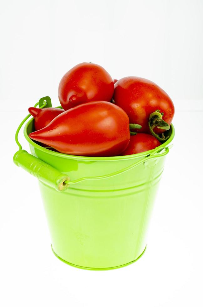 oogsten. rode rijpe tomaten in gekleurde emmers op witte achtergrond. studiofoto. foto