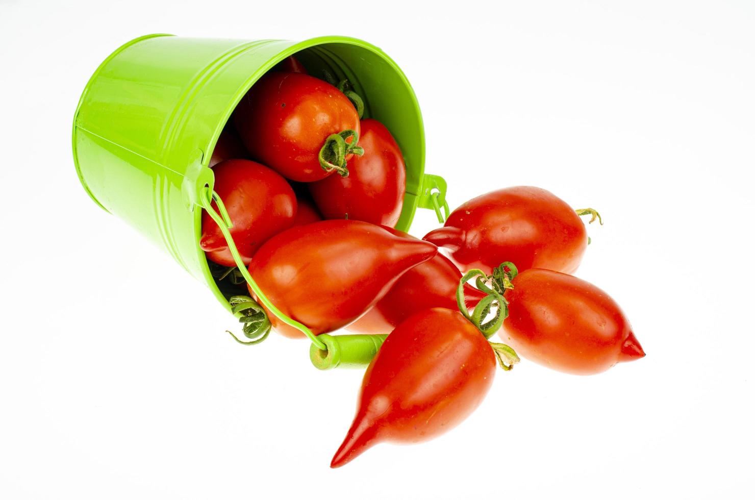 oogsten. rode rijpe tomaten in gekleurde emmers op witte achtergrond. studiofoto. foto