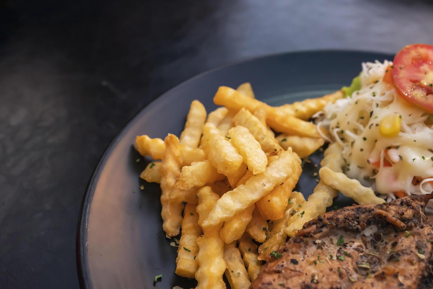 zwart peper gemarineerd kip filet met aardappel stokjes Aan een zwart bord foto