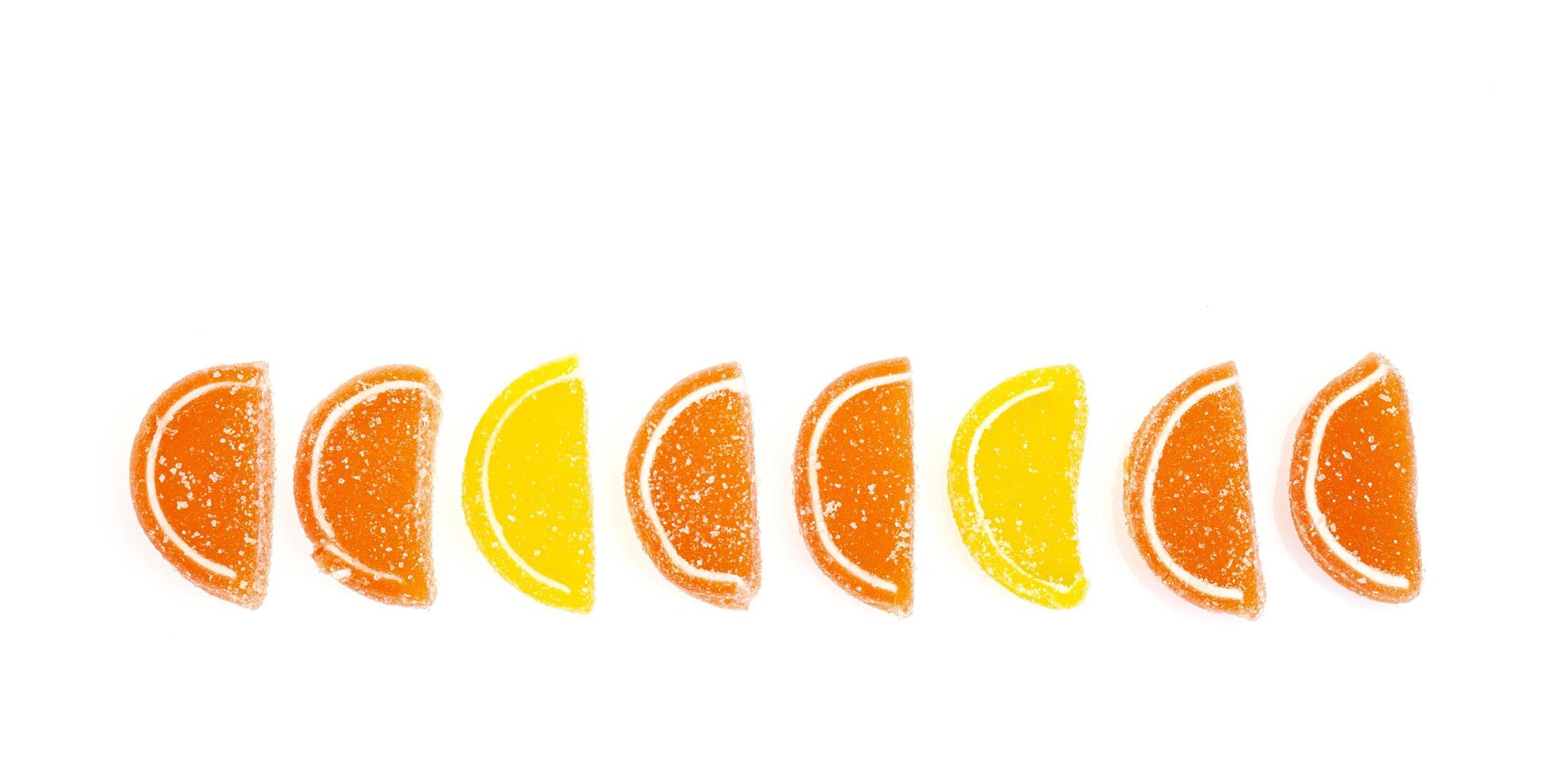 Oranje en gele plakjes zoete fruitmarmelade in suiker geïsoleerd op een witte achtergrond foto