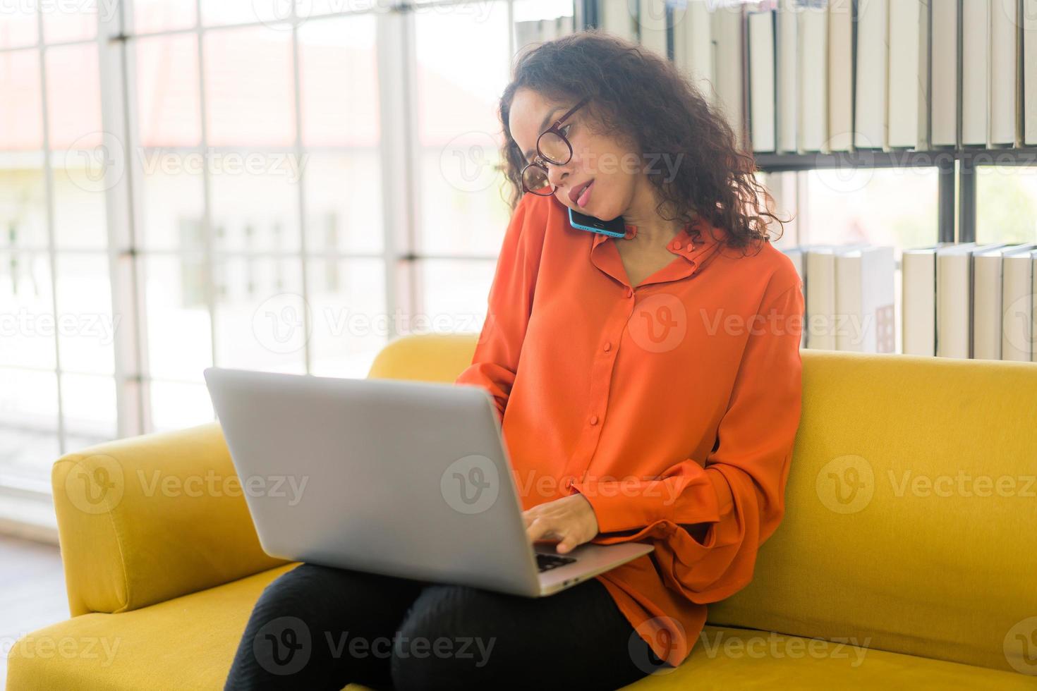 Latijnse vrouw die met laptop op bank werkt foto