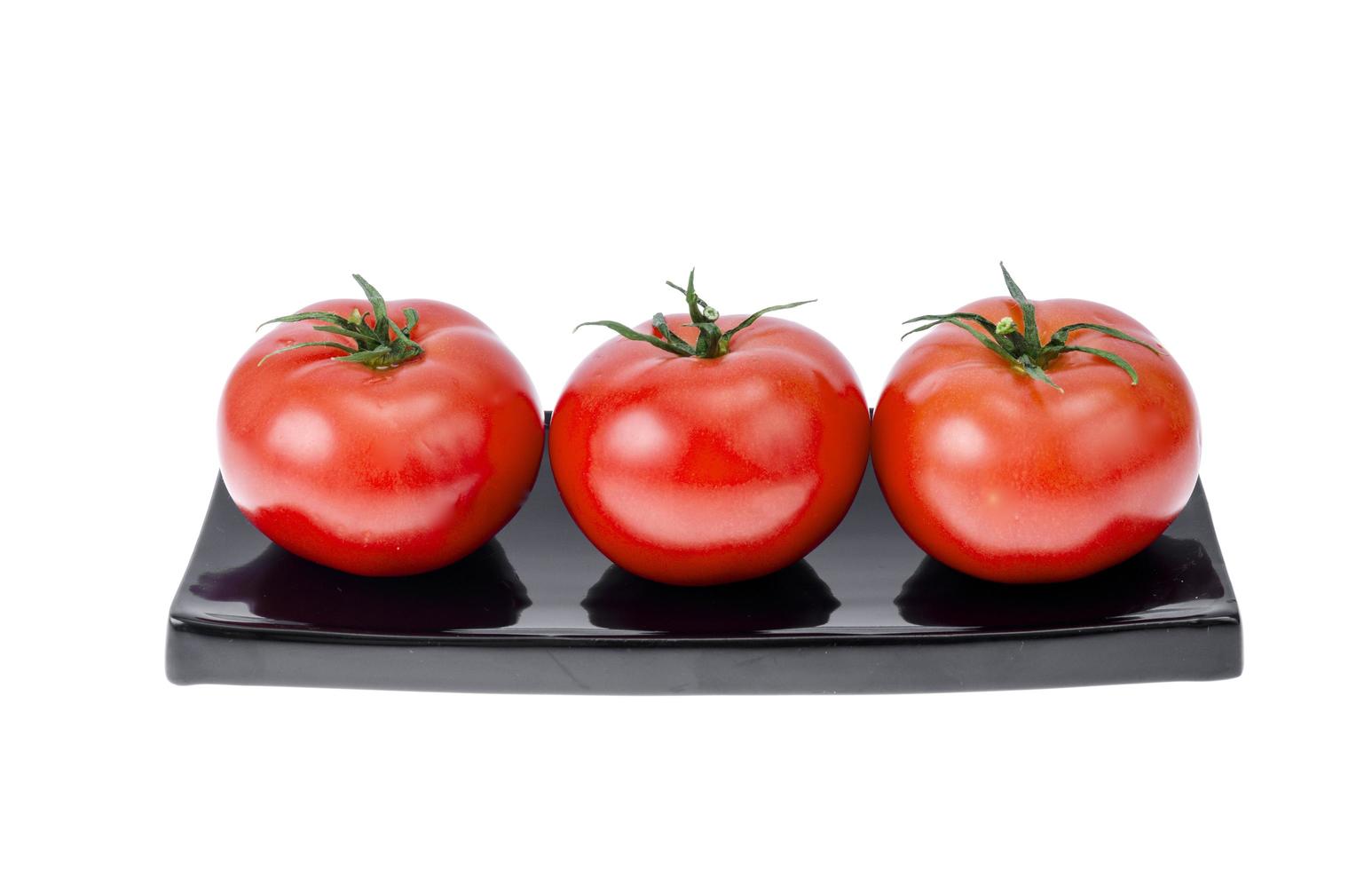 drie rijpe rode tomaten op zwarte plaat foto