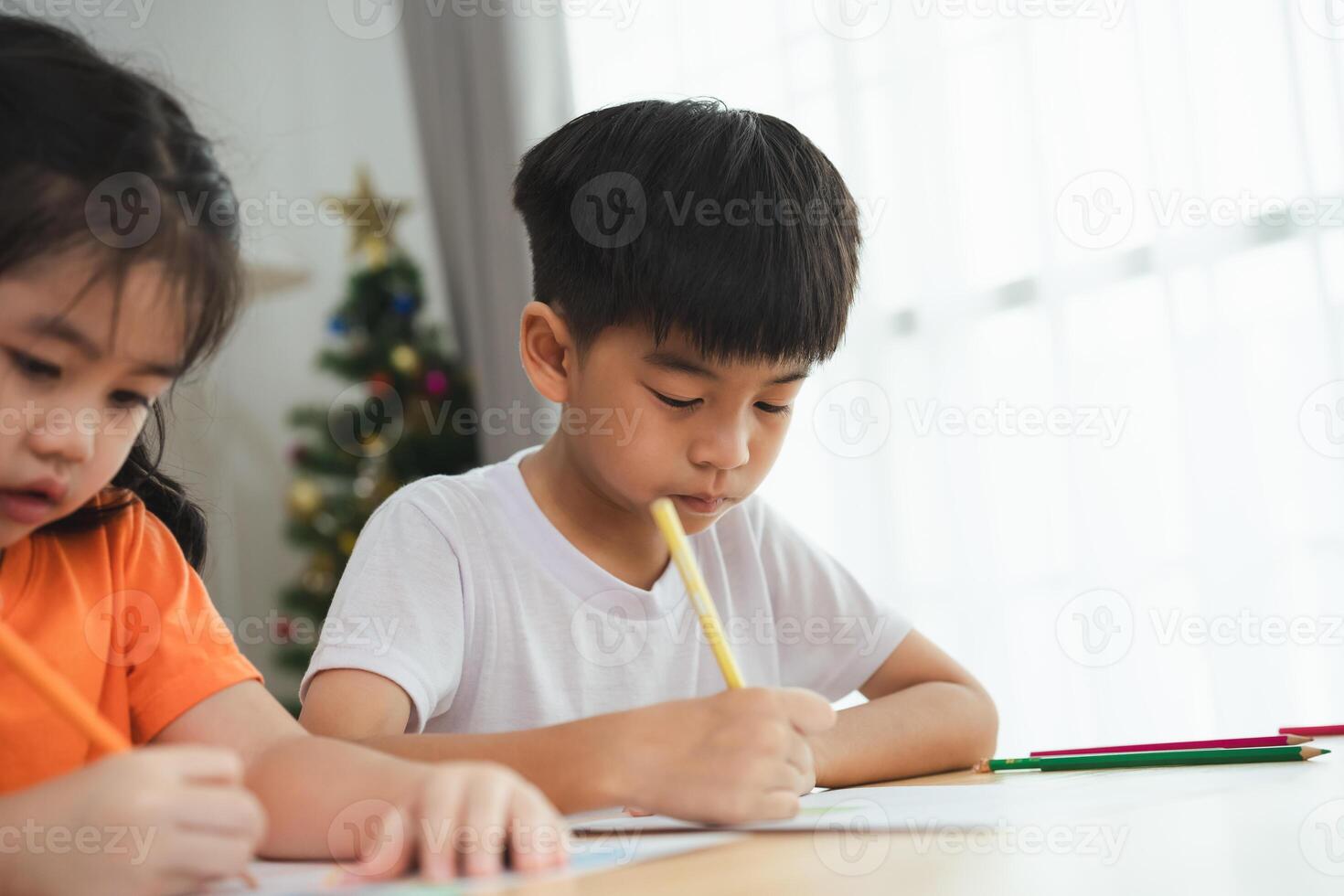 een jongen is schrijven met een potlood terwijl een meisje horloges. de meisje is vervelend een oranje overhemd foto