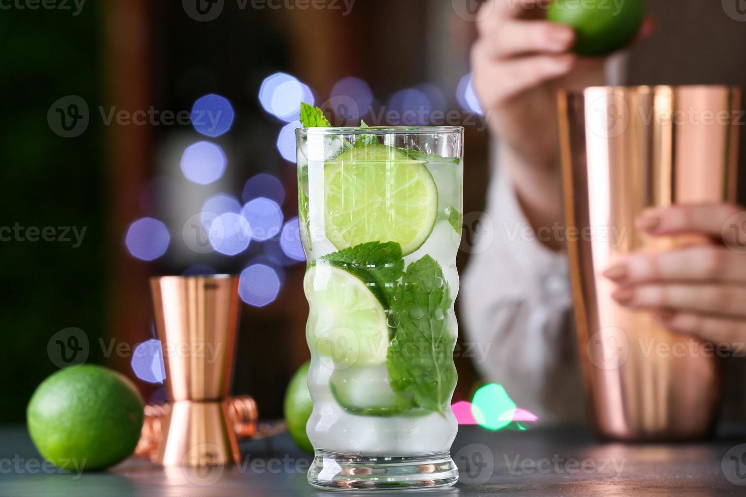 vrouwelijke barman met glas verse mojito op tafel in bar foto