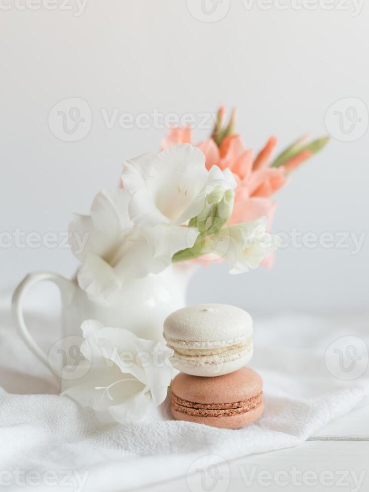 twee pastel Frans macarons en bloemen in een pot Aan een wit achtergrond. foto