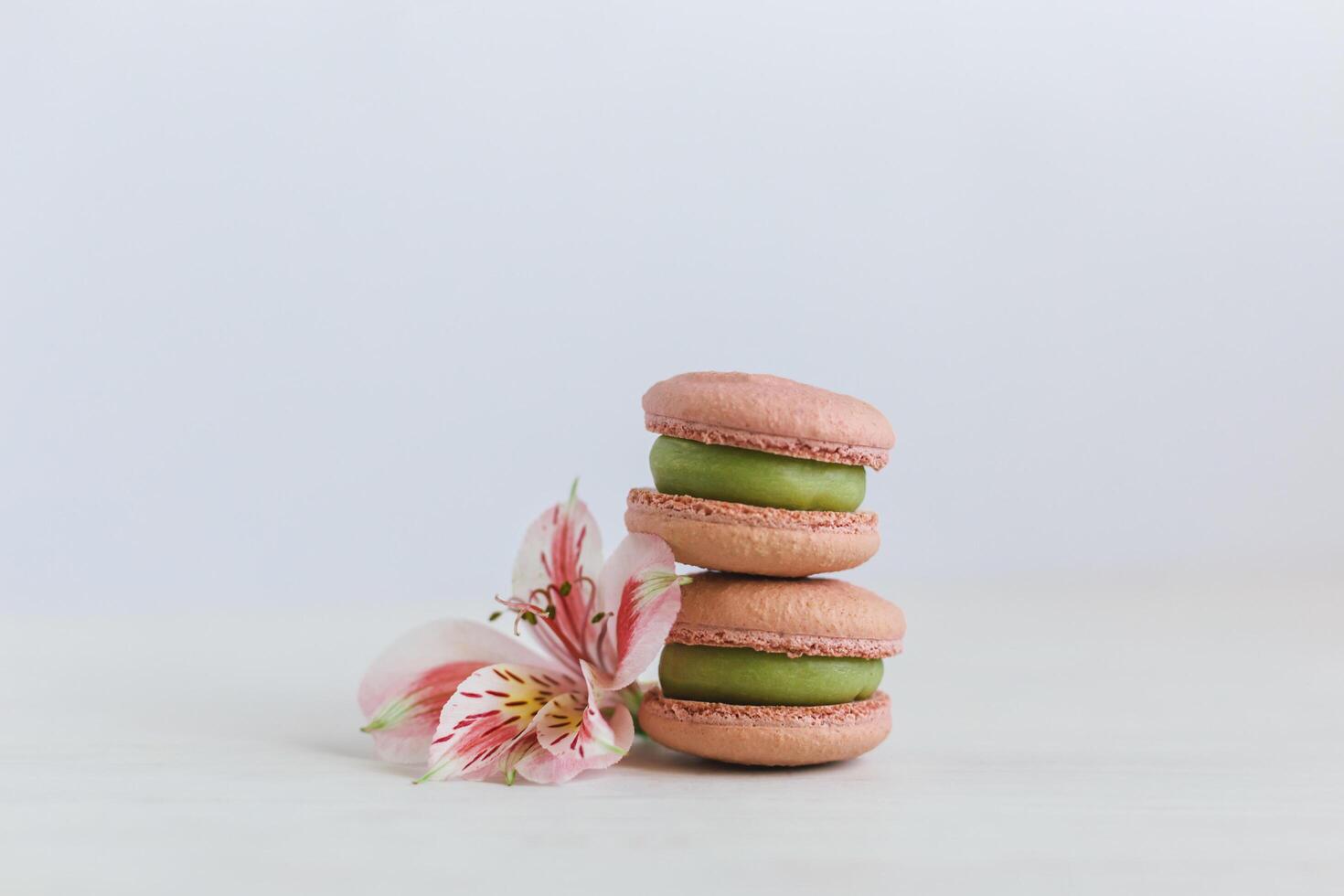 twee smakelijk Frans macarons met roze bloem Aan een wit achtergrond. foto
