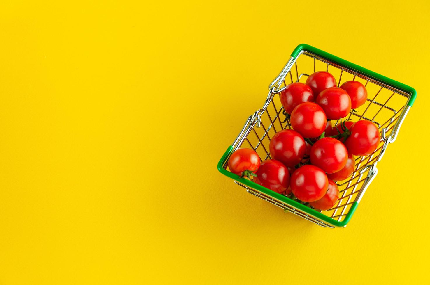 cherrytomaatjes in een mand op een felgele achtergrond met een lege plek voor een inscriptie. foto