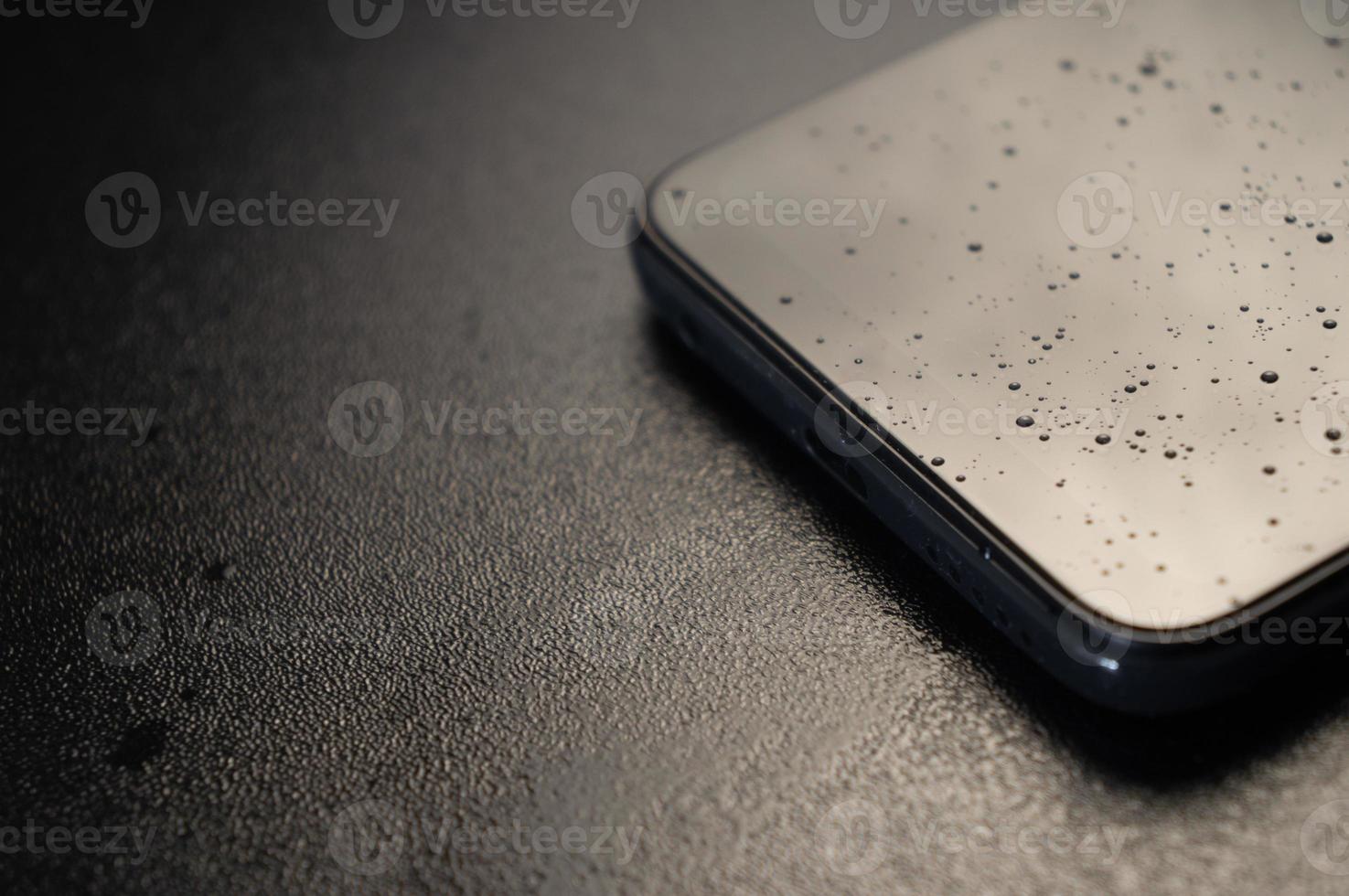 zwarte smartphone in spatten van vloeistof op een zwarte achtergrond foto