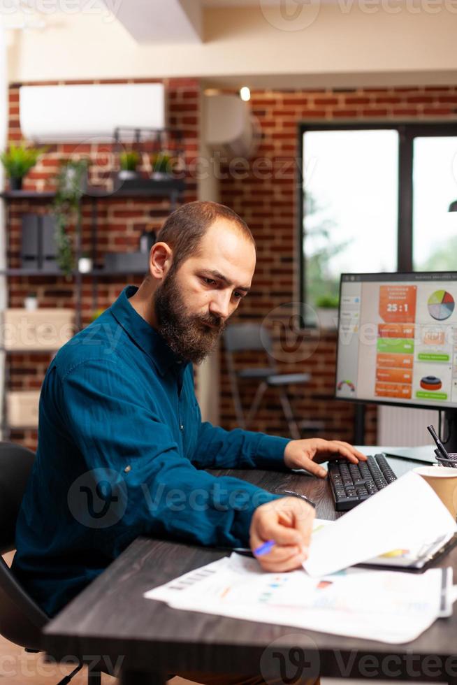 zakenman zit aan bureau en analyseert zakelijk papierwerk bij managementpresentatie foto