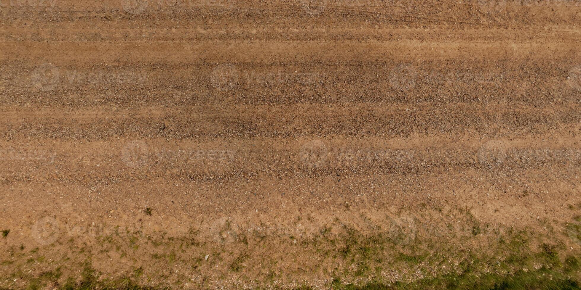 visie van bovenstaand Aan structuur van droog modderig weg met trekker band sporen in platteland foto