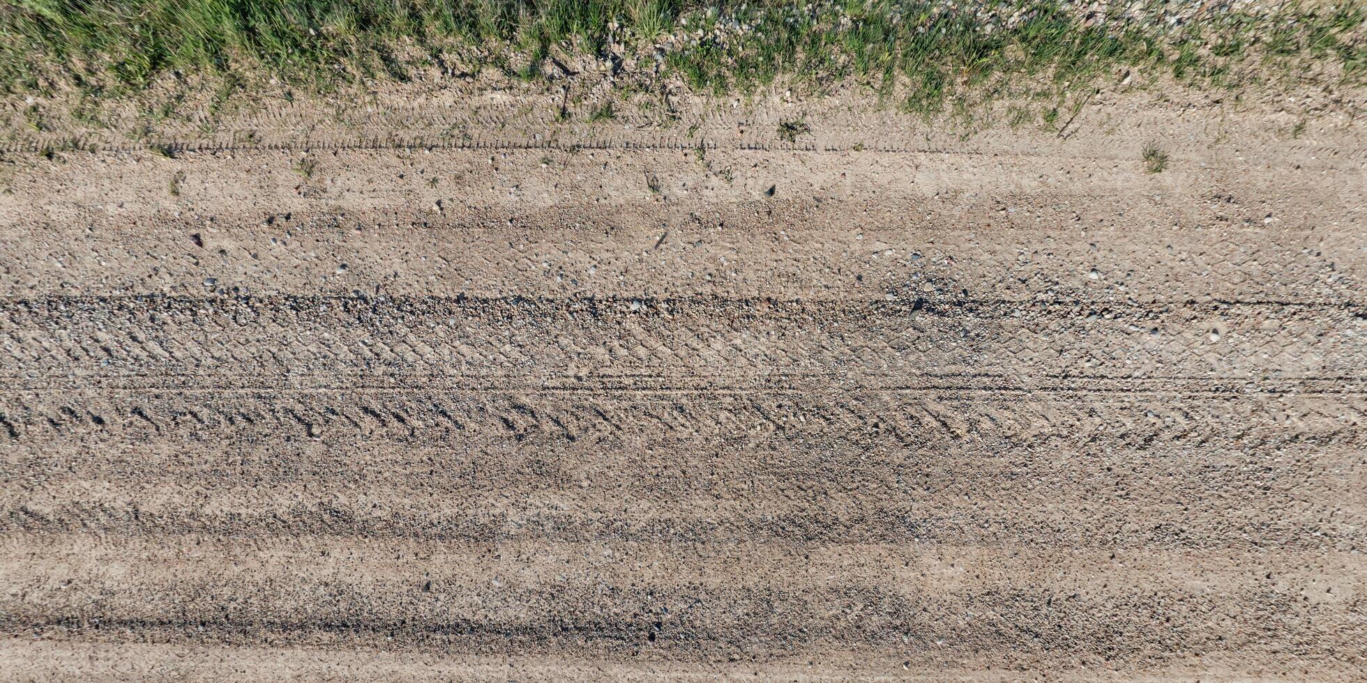 visie van bovenstaand Aan structuur van droog modderig weg met trekker band sporen in platteland foto