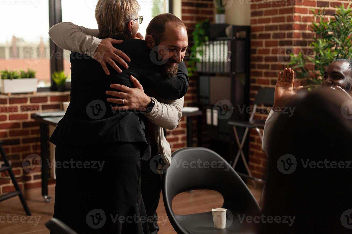 man en psycholoog knuffelen na het delen van verslavingsvoortgang met een vergadergroep foto