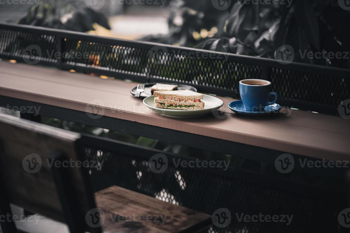 sandwich en warme koffie op houten bar foto