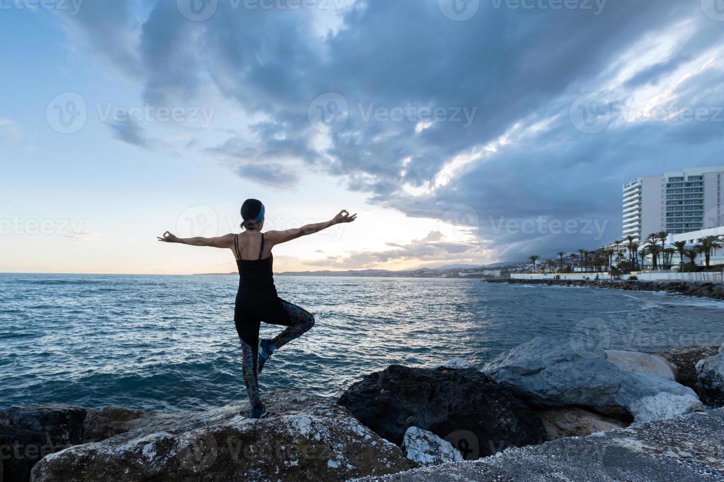 vrouw die yoga beoefent met uitzicht op zee op een bewolkte dag foto