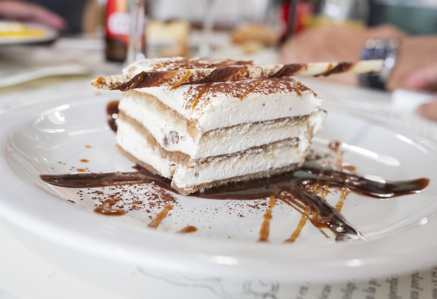 stukje meringuetaart met chocoladeschilfers en zwarte chocoladesiroop op het bord foto