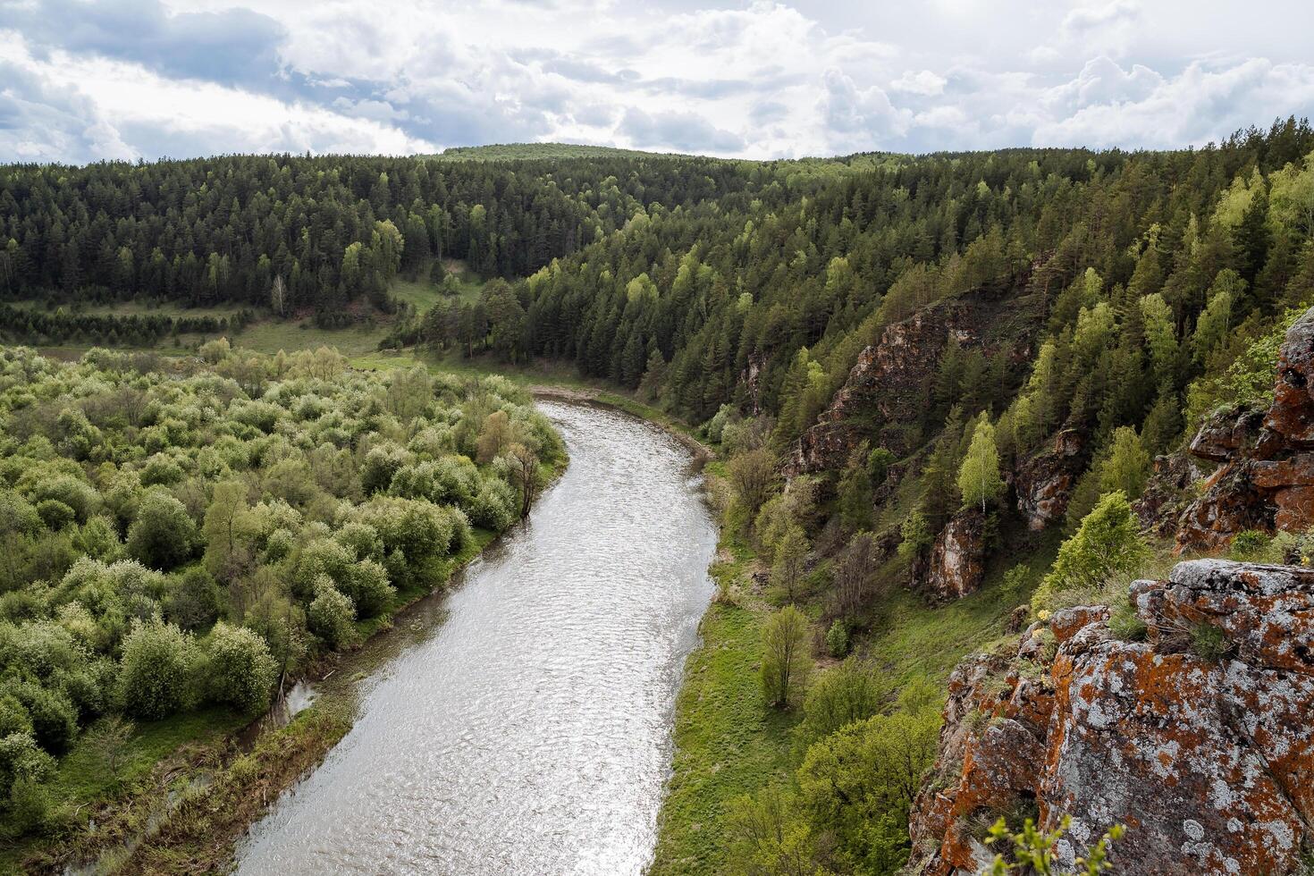 de natuur van Rusland, de taiga Oppervlakte, de Gereserveerd land, de landschap van de berg rivier, de oranje rots tegen de achtergrond van de groen Woud, de bewolkt lucht. foto