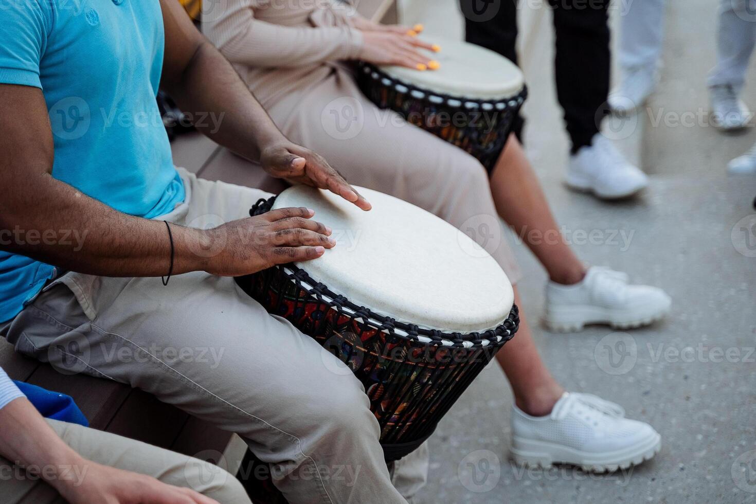 een sterk gespierd vent drums Aan een djemba, een straat musicus, drummers ritme de ritme van jazz- in openbaar, handen Speel Aan percussie. foto