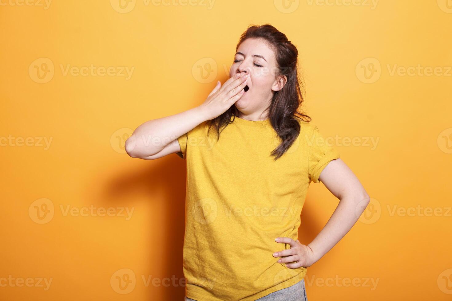 portret van Kaukasisch vrouw geeuwen en aan het bedekken haar mond, gevoel slaperig in studio. moe vrouw persoon vallend in slaap terwijl poseren en staand over- geïsoleerd achtergrond. foto