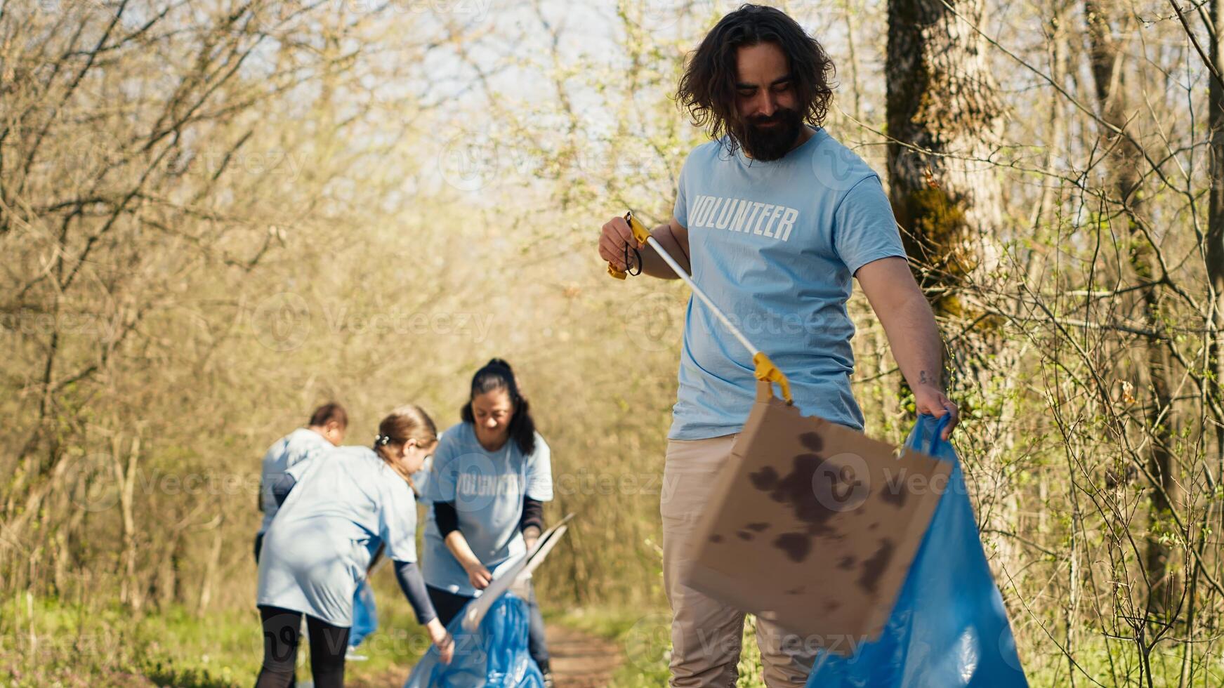 Mens activist gebruik makend van tang naar grijp vuilnis en plastic afval, plukken omhoog uitschot en schoonmaak de Woud Oppervlakte. vrijwilliger sorteren onzin en recycling het, bewaren de natuur. camera a. foto