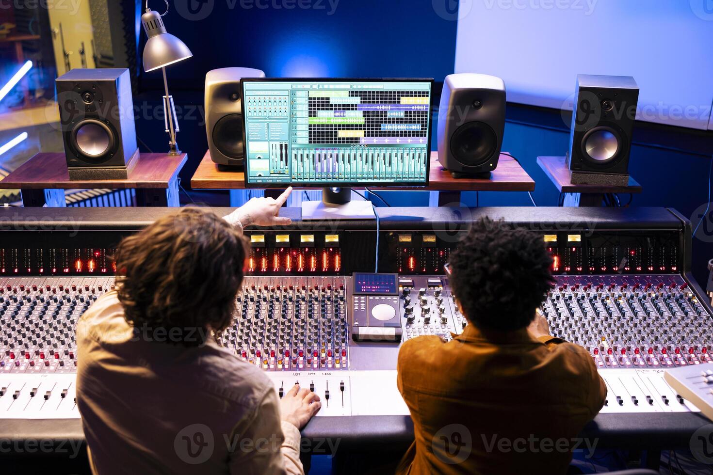 audio ingenieur en artiest samenwerken Aan nieuw liedjes voor knal album, componeren en bewerken deuntjes met menging troosten en digitaal software. musicus werken met technicus Aan records in studio. foto