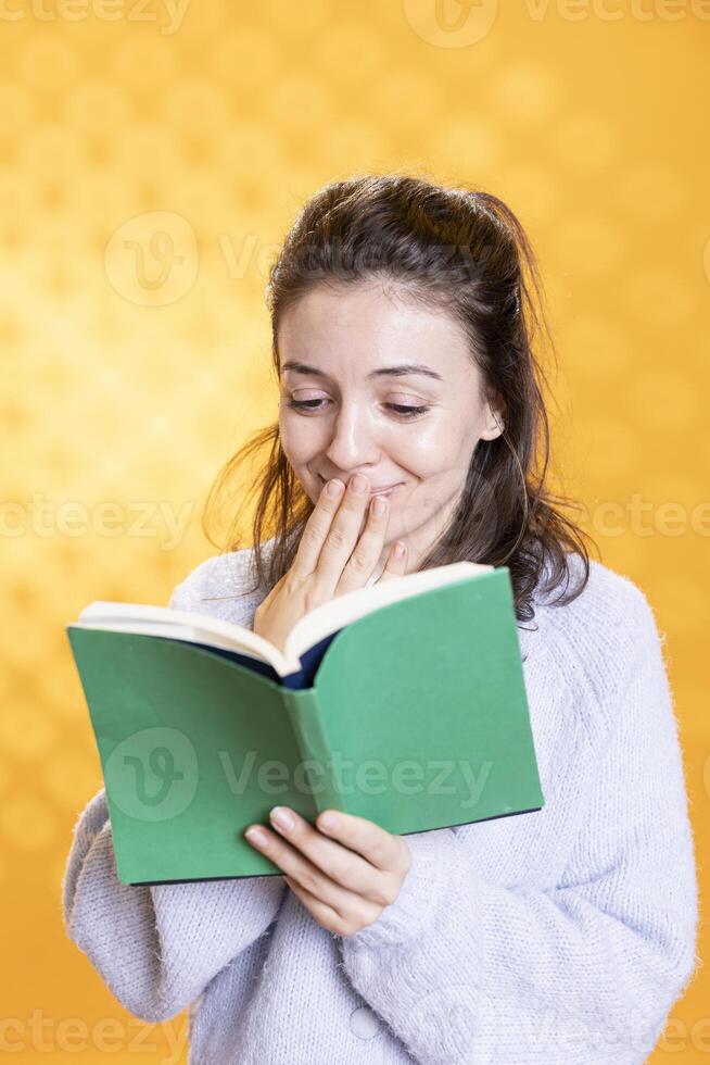 vrouw geamuseerd door grappig boek, overbrengen vreugde van lezing concept, geïsoleerd over- studio achtergrond. geek genieten van komisch roman, giechelen Bij grappen, tonen waardering voor literatuur foto