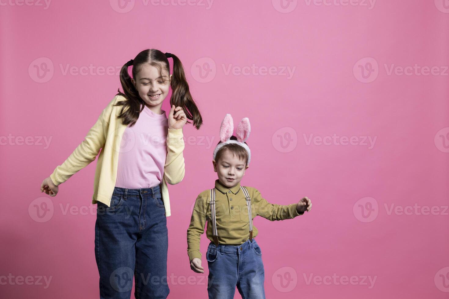 schattig jong kinderen dansen in de omgeving van in voorkant van camera, gevoel gelukkig en nieuwsgierig over Pasen viering of geschenken. broer en zus genieten van voorjaar vakantie, weinig jongen vervelend konijn oren. foto