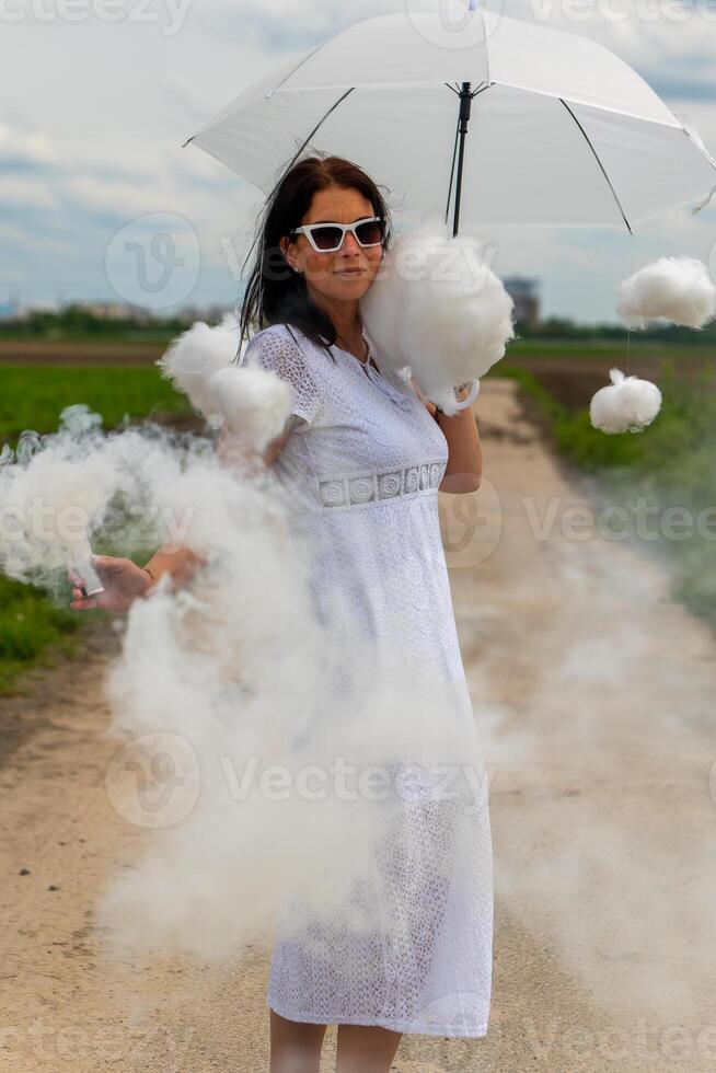 mooi vrouw in een wit jurk en schattig wolken met rook met een paraplu foto